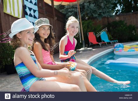 Smiling Girls Sitting At Poolside Dipping Feet In Water Stock Photo Alamy