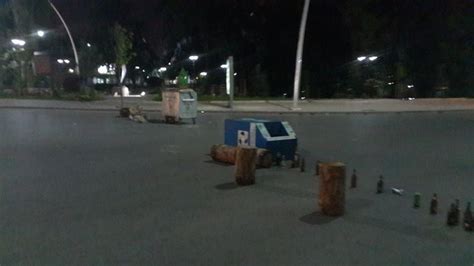 An Empty Parking Lot At Night With Trees And Trash Cans On The Ground