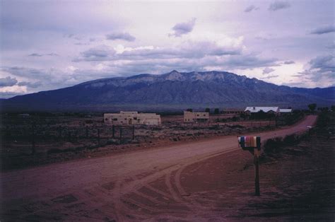 A Dirt Road In The Middle Of Nowhere With Mountains In The Backgrouds
