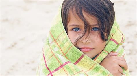 cute little latin girl at beach covered with green towel looking into the camera stock image