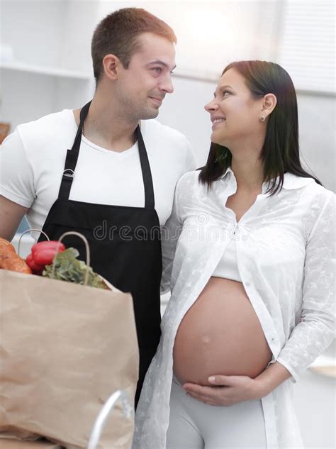 Husband And His Pregnant Wife Are Combing Through The Packstanding In The Kitchen Stock Image