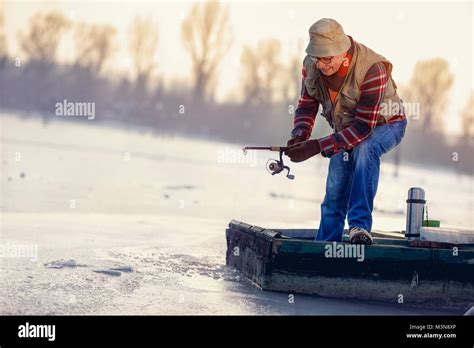 Winter Season Smiling Fisherman Fishing On The Frozen Lake Stock