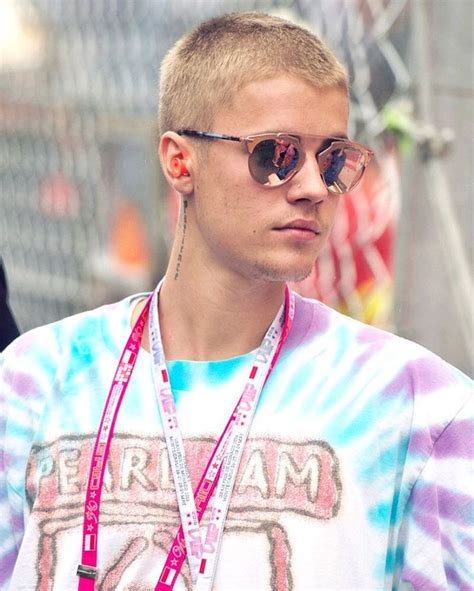 A Man With Sunglasses And A Tie Dye Shirt Holding A Cell Phone In His Hand