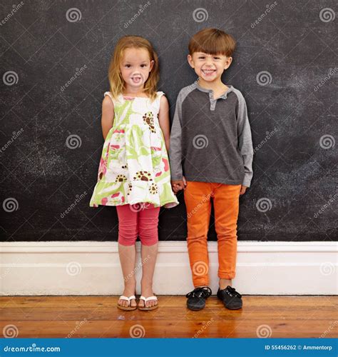 Two Little Kids Standing Together Against Blackboard Stock Photo