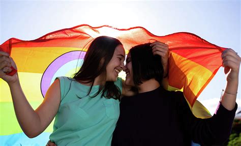 beautiful lesbian couple having fun in the street with a lgtb flag photograph by cavan images