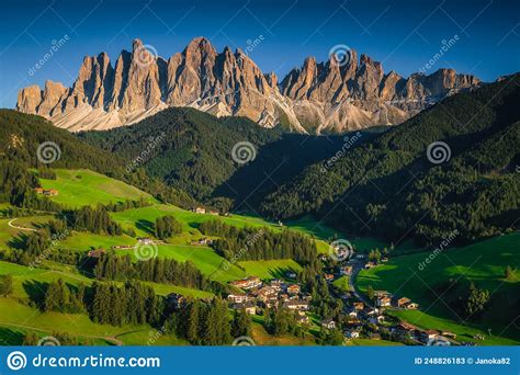 Picturesque Alpine Village With Green Fields And Mountains Funes