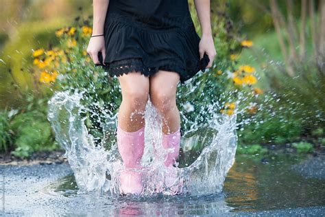 Woman With Pink Rain Boots Splashes In A Puddle Stocksy United