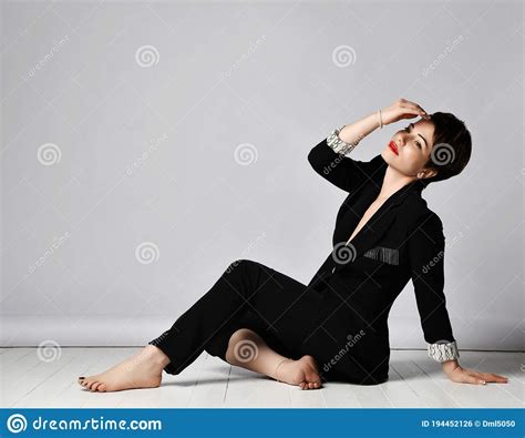 Beautiful Short Haired Brunette Woman In Elegant Business Pantsuit And Barefoot Is Sitting On