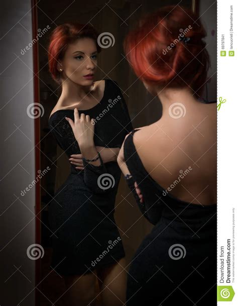 Attractive Redhead With Black Dress Posing In Front Of Large Wall