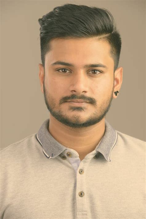 Face Of Young Handsome Bearded Indian Man Wearing Hoodie Stock Photo