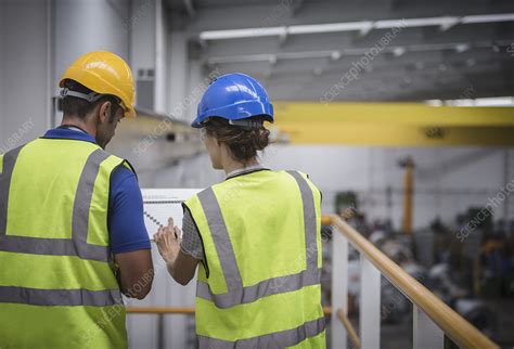 Supervisors Discussing Paperwork On Platform In Factory Stock Image