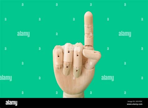 Wooden Hand With Raised Index Finger On Color Background Stock Photo