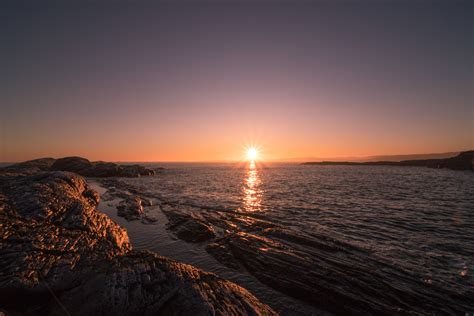 Free Photo Brown Rocks Beside Body Of Water During Sunset Sun
