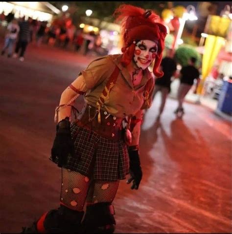 A Woman Dressed Up As A Clown Walking Down The Street At Night With