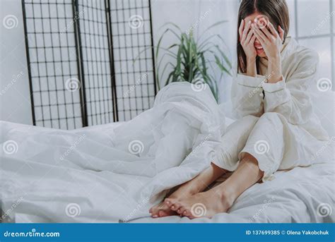 Depressed Asian Woman Sitting On Bed In Cozy Apartment Stock Image