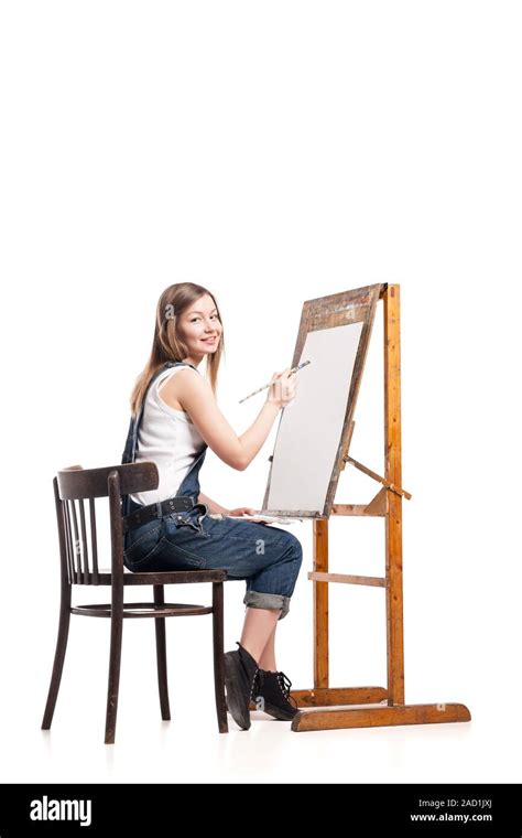Young Smiling Woman Painter With Paintbrush Standing At Easel Stock