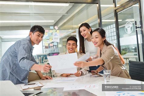 Professional Smiling Young Asian Business Team Working With Papers In