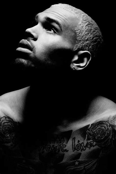 a black and white photo of a man with tattoos on his chest looking up