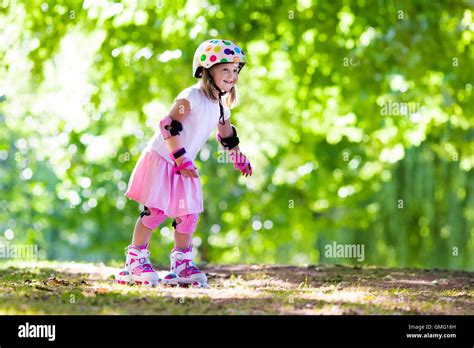 Little Girl Learning To Roller Skate In Sunny Summer Park Child