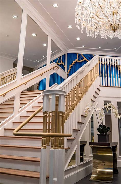 An Elegant Staircase With Chandelier And White Railings In A Large Room