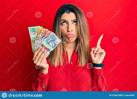 Beautiful Brunette Woman Holding Australian Dollars Pointing Up Looking Sad And Upset