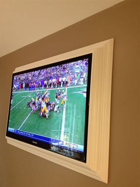 A Flat Screen Tv Mounted On The Wall In A Room With People Watching And