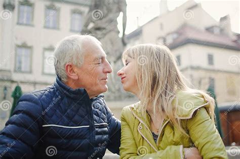 Portrait Of Happy Romantic Couple With Age Difference Kissing Outdoors