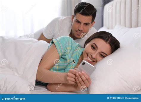 Distrustful Man Peering Into Girlfriend`s Smartphone Jealousy In Relationship Stock Image