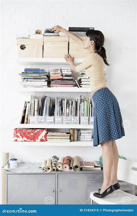 Businesswoman Reaching For Shelf In Home Office Stock Image Image Of