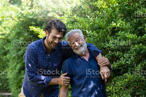 Smiling Senior Father With Adult Son Embracing And Talking Outdoor Garden Elderly Father And