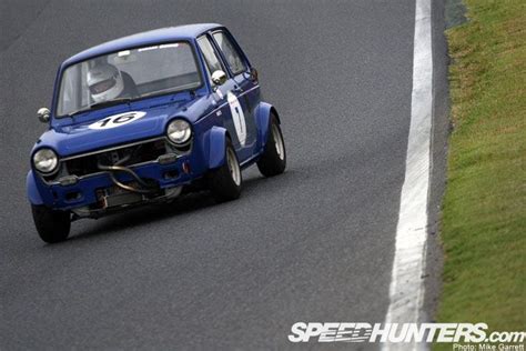 A Small Blue Car Driving Down A Race Track