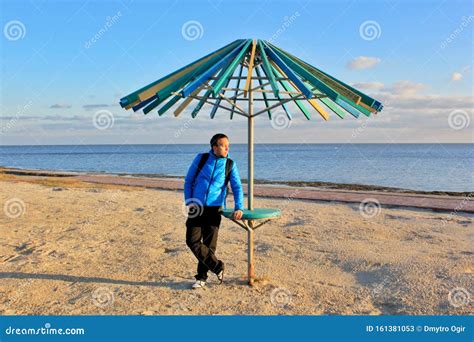 Solo Traveling Man Under The Sun Umbrella On The Beach With Sea