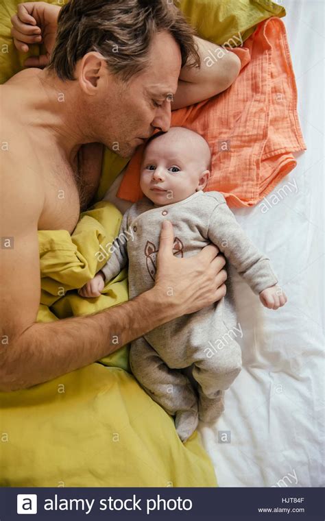 Father Cuddling In Bed With His Newborn Baby Stock Photo Alamy