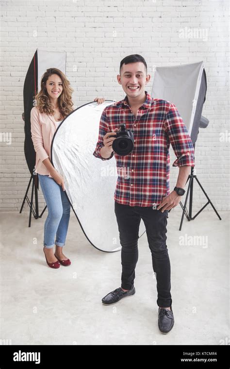 Young Photographer With His Beautiful Assistant In Studio Stock Photo