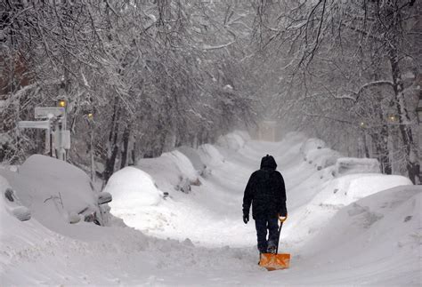 A Man Drags A Shovel Up Beacon Hill During A Severe Winter Snow Storm