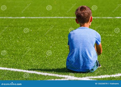 Sad Alone Boy Sitting In Soccer Field Stadium Outdoors Stock Photo