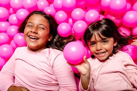 Dos Niñas Sonriendo Y Jugando En La Piscina De Bolas Rosa Foto Premium