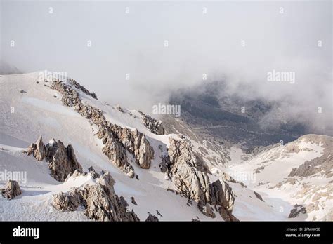 Snowy Mountain Peaks Surrounded With Clouds And Fog Stock Photo Alamy
