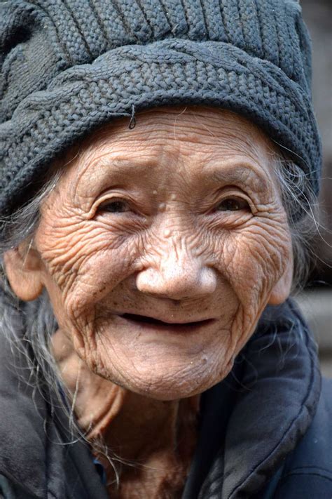 An Old Woman With Wrinkles And A Hat On Her Head Smiling At The Camera