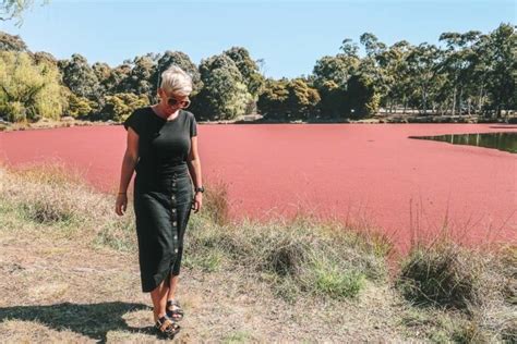An Older Woman Is Walking Near A Red Lake