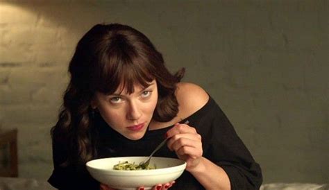 A Woman Holding A Bowl Of Food In Front Of Her Face