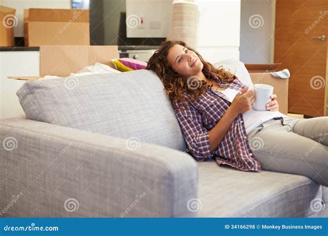 frau die auf neuem haus sofa with hot drink ins sich entspannt stockfoto bild von