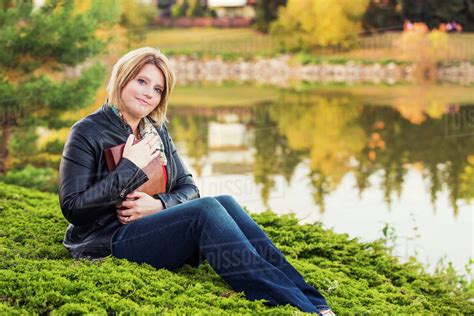 mature christian woman embracing her bible in a park beside a lake in autumn edmonton alberta