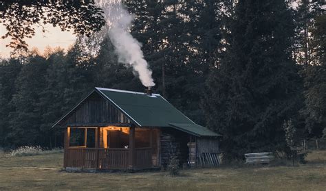Cabin With Smoke Coming Out Of Chimney Near Trees Photo