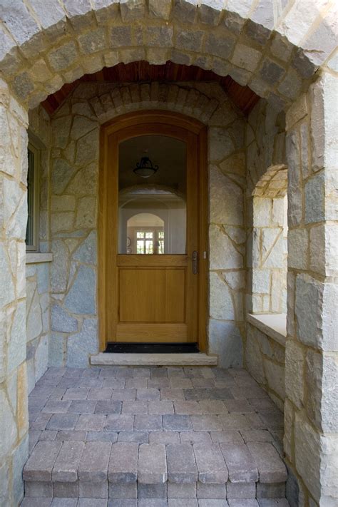 Stone Covered Arch Entry With Glass And Wood Arch Top Front Door And