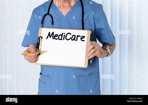 Senior Male Caucasian Doctor With Stethoscope In Medical Scrubs And Holding Clipboard For