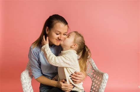 Hija Besa A Su Madre En Una Pared Rosa Foto Premium