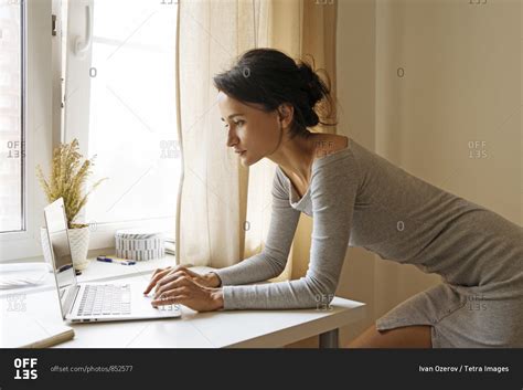 Woman Leaning On Table Using Laptop Stock Photo OFFSET