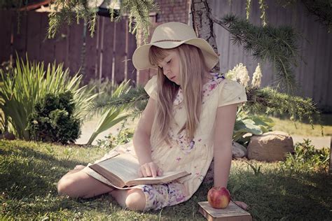 free photo girl in white and blue dress reading books while sitting on lawn grass person