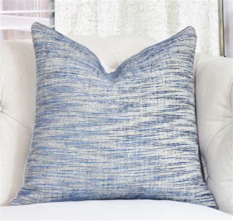 A Blue And White Pillow Sitting On Top Of A Couch In Front Of A Window